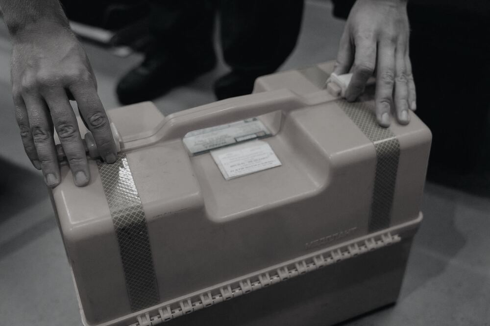 A courier taking possession of a sealed medical transport case at handover.